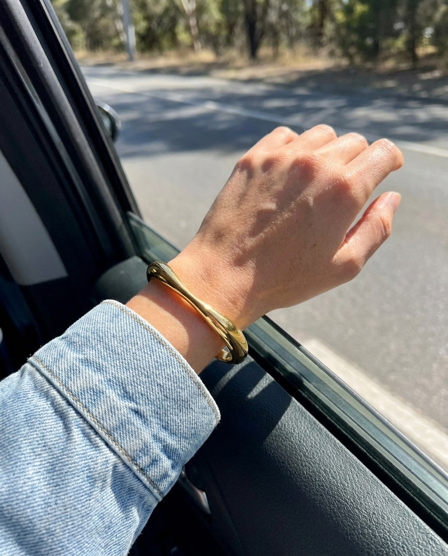 Maya Gold Bangle Bracelet on a wrist out of a car window